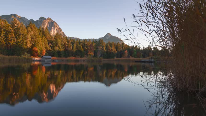 Shadows gradually cover the forest and mountains surrounding a clear lake