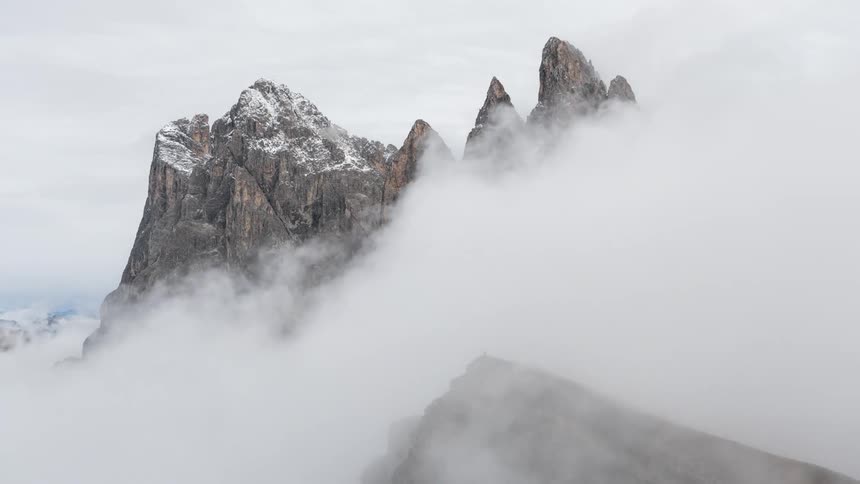 Through the clouds the peak of a mountain peeks through