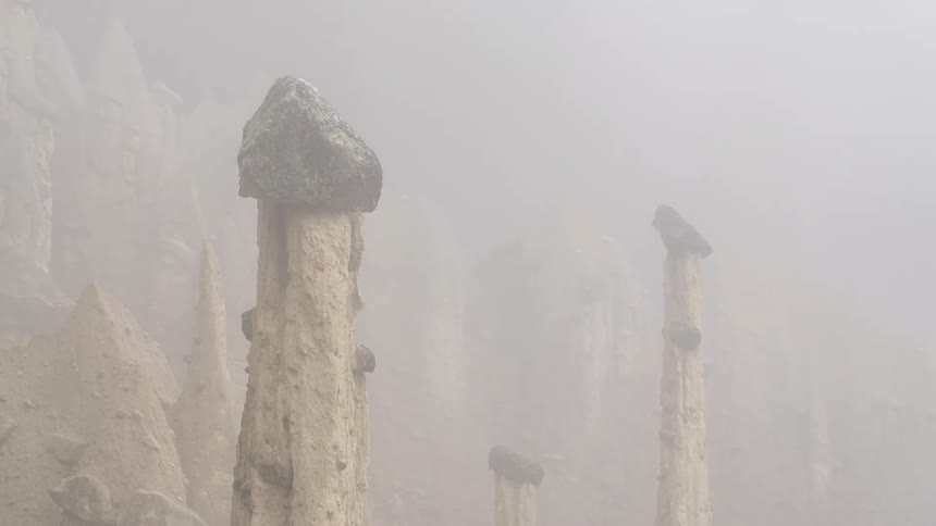 Series of thin tall stone pilings with fog disappearing around them
