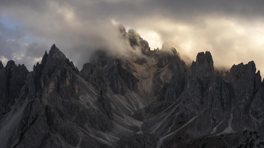 The majestic peaks of the dolomites are shrouded in clouds and fog