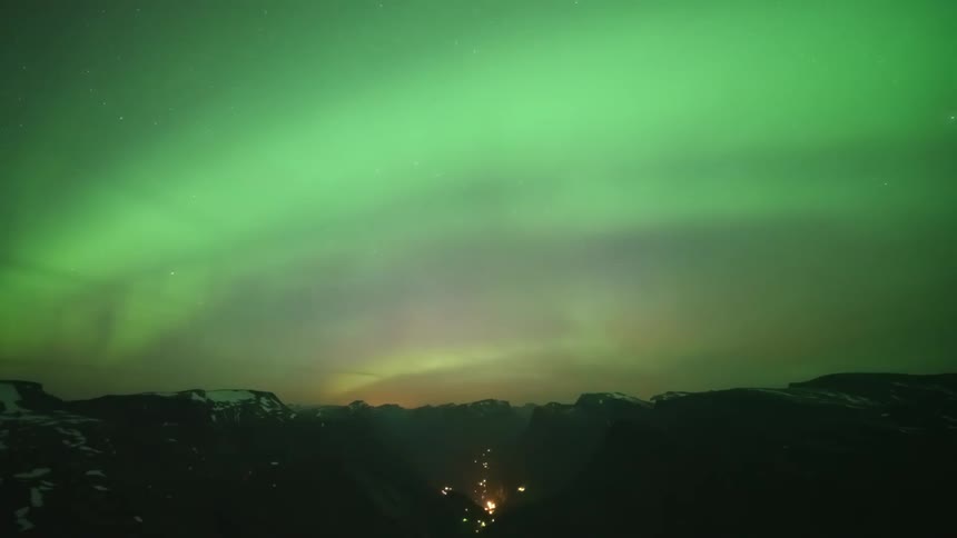 Night landscape of mountain silhouettes with snowcapped peaks and a sky with northern lights