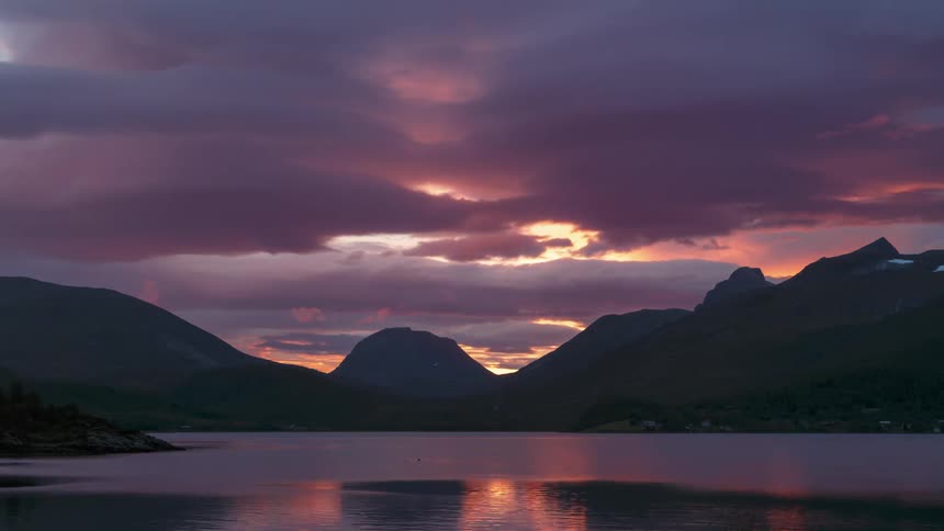 Town sits between the mountains and a body of water that reflects the red sky at sunset