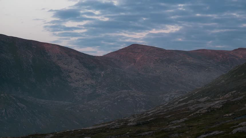 Mountainous landscape at dusk with dense clouds and fog