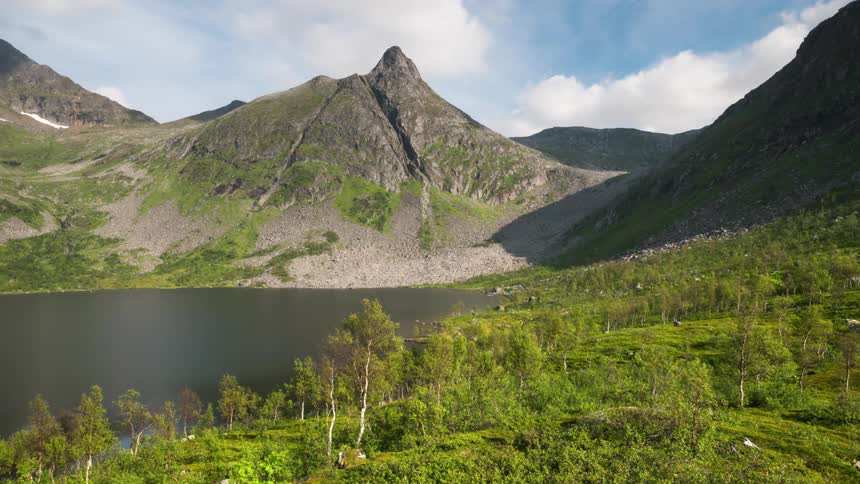 Lake surrounded by mountains and vegetation on a partly cloudy day