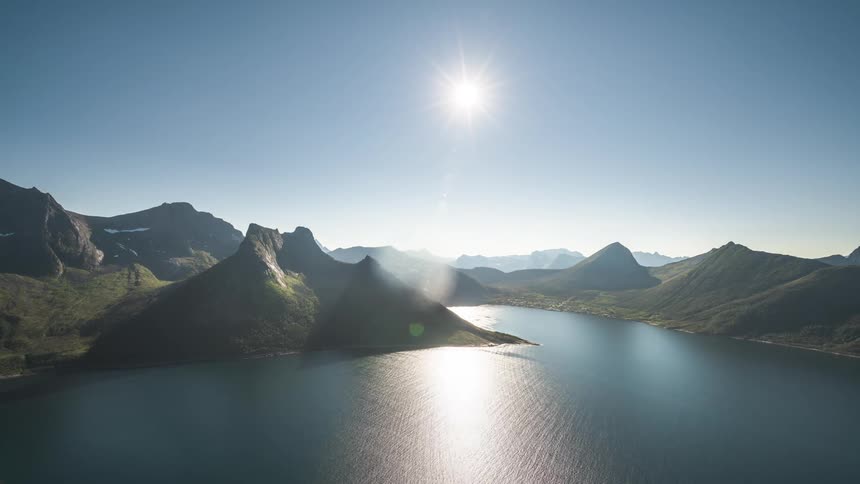Landscape of mountains surrounded by the sea and the moving sun