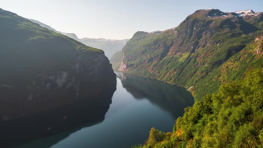 Maritime canal surrounded by greenish mountains in a morning sky