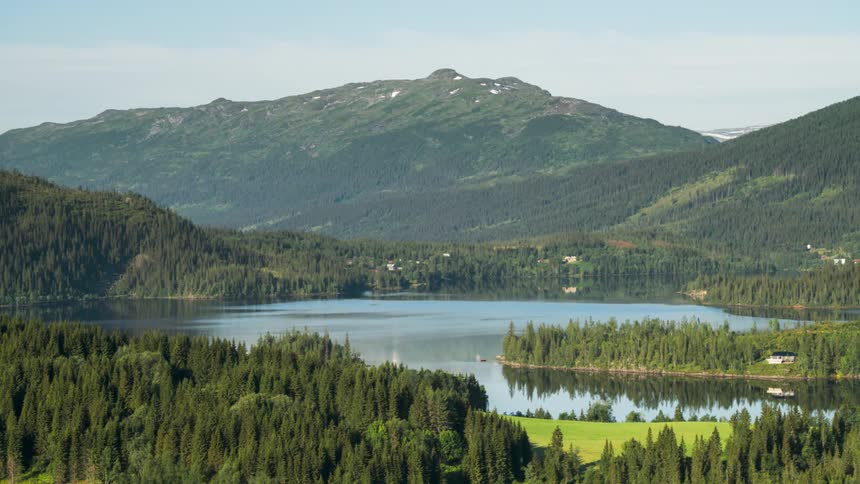 Houses dot lakeside forest near towering mountains