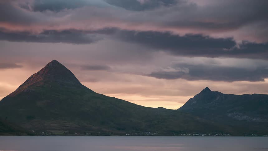 Mountains by the sea against a cloudy sky