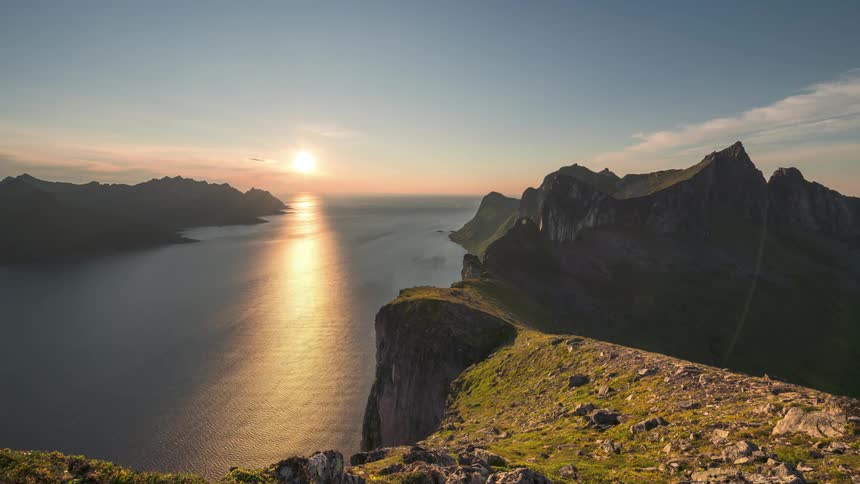 Landscape of the rocky coast with sun reflection on the horizon and reflecting in the sea