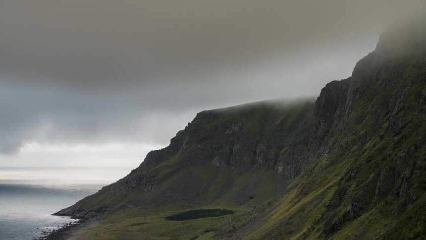 Clouds skim mountain peaks as the tide rolls in
