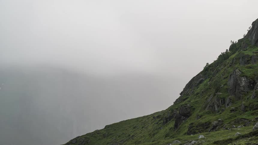 Mountain range with mosses and dense fog passing by