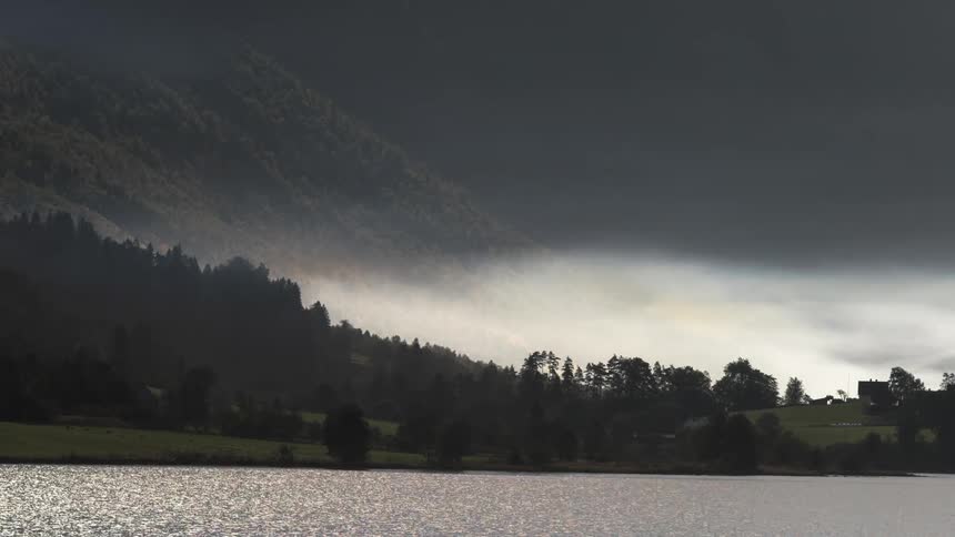 Dark clouds move over a rural area near a lake shore