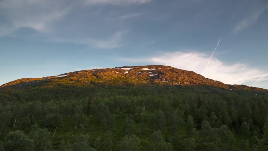 Mountain with a greenish forest and the sky turning purple in the late afternoon
