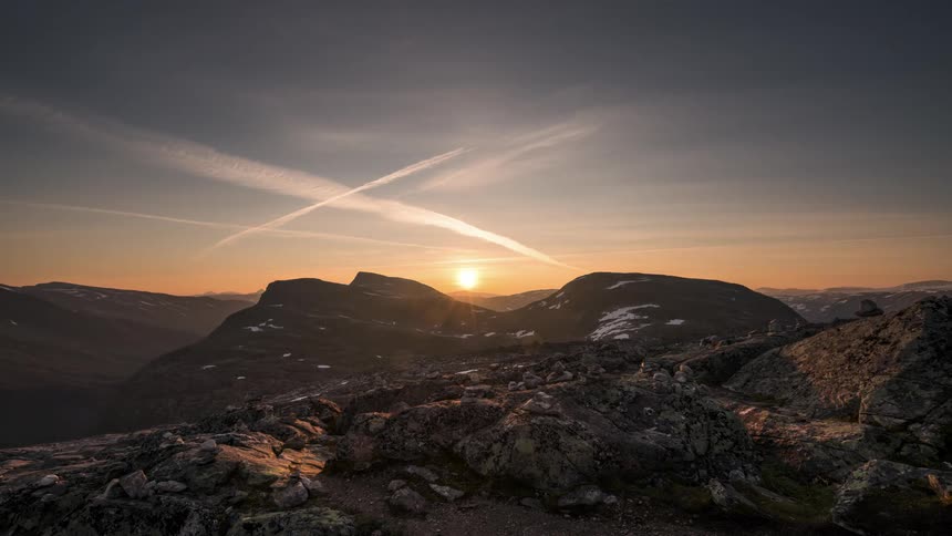 Mountainous landscape with the sun rising on the horizon