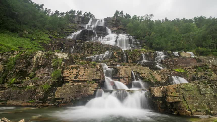 Mountain wall with stream and a waterfall on a cloudy day