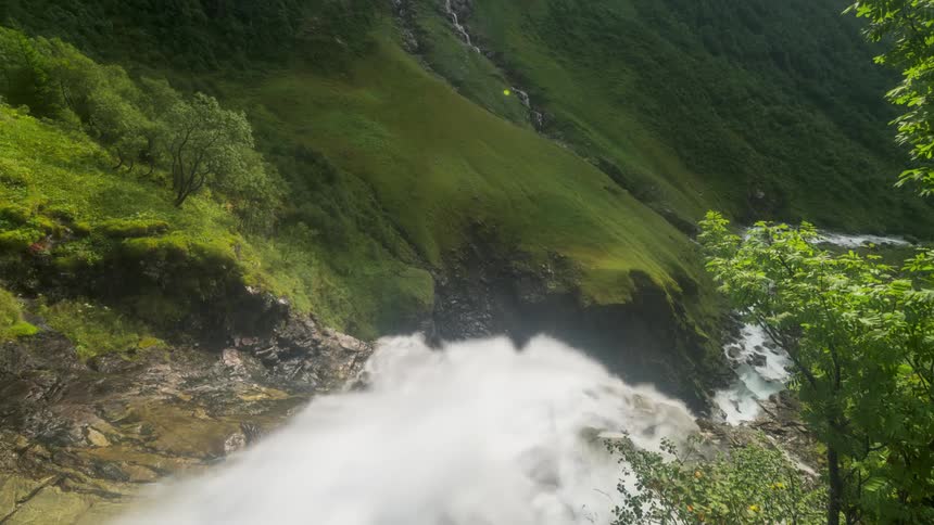 A small river turns into a waterfall in a green mountain valley