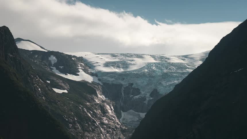 Rocky mountains with snow and dense clouds passing above