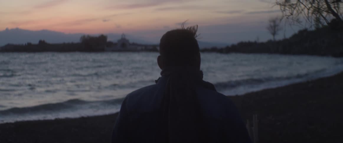 A man walks near the beach at dusk