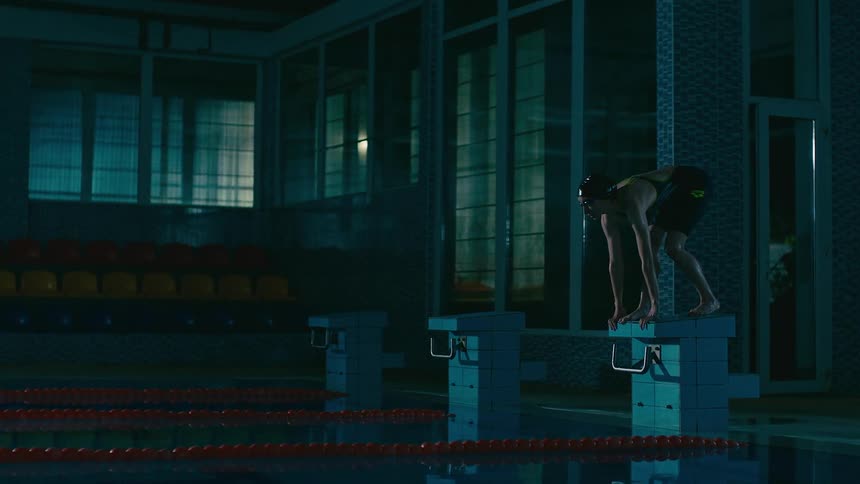 A girl is diving into a swimming pool during the night time