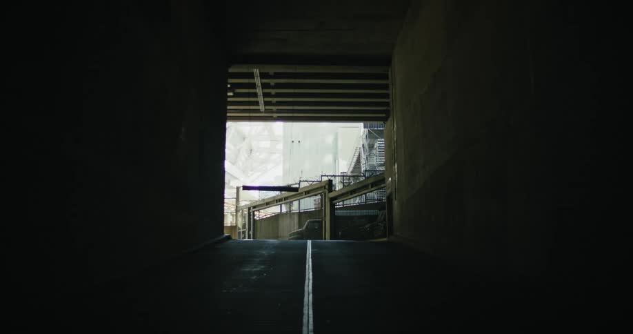 An illuminated underpass with a concrete road stretching through it
