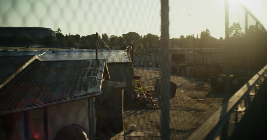 A chainlink fence frames an industrial area during sunset