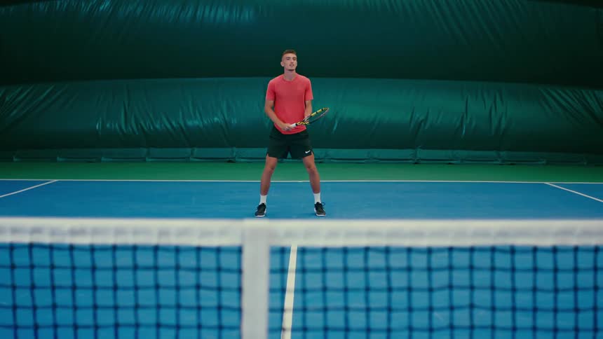 A man plays tennis on a court inside of an inflatable structure