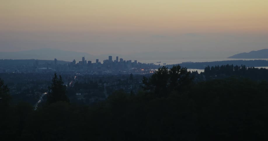Silhouette of an urban skyline at twilight with buildings outlined against a gradient orange to blue sky