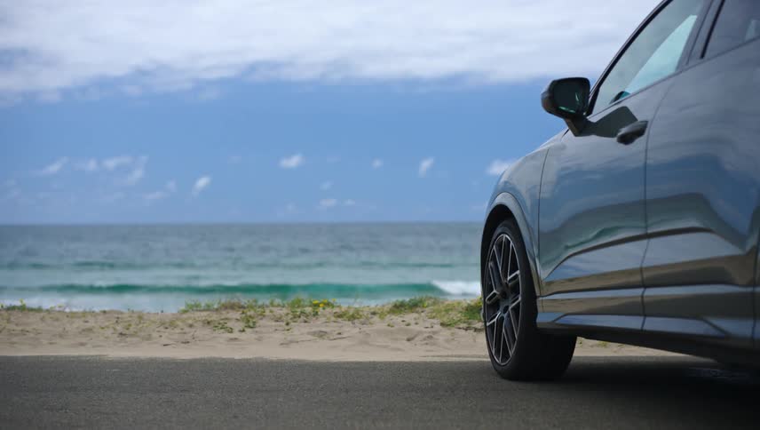 Side of a car parking on a street near a beach