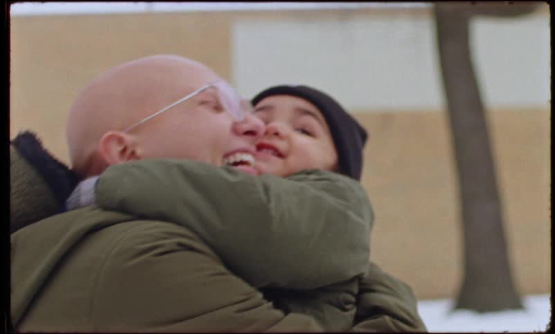 A mother happily picks her son up off the snow covered ground