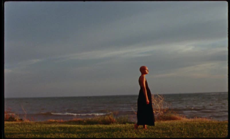 A woman is walking on the coast of a beach at dusk