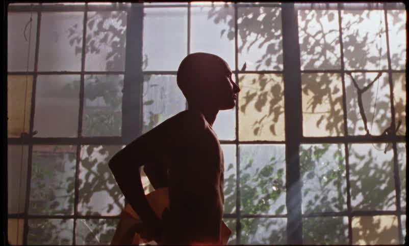 A person is standing near a window and is stretching