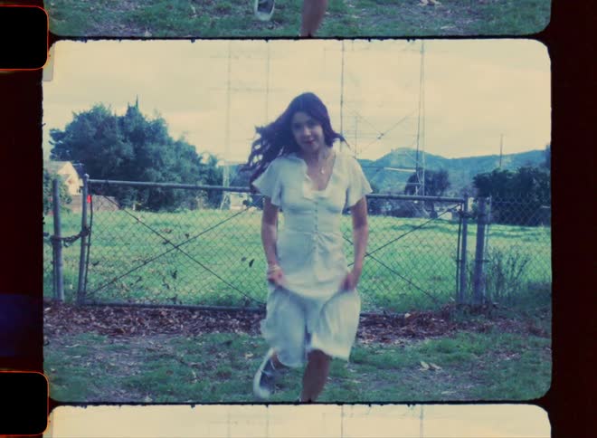 Smiling woman wearing a long white dress and running in an open field