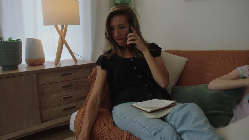 Woman is sitting on a couch and talking on a cellphone