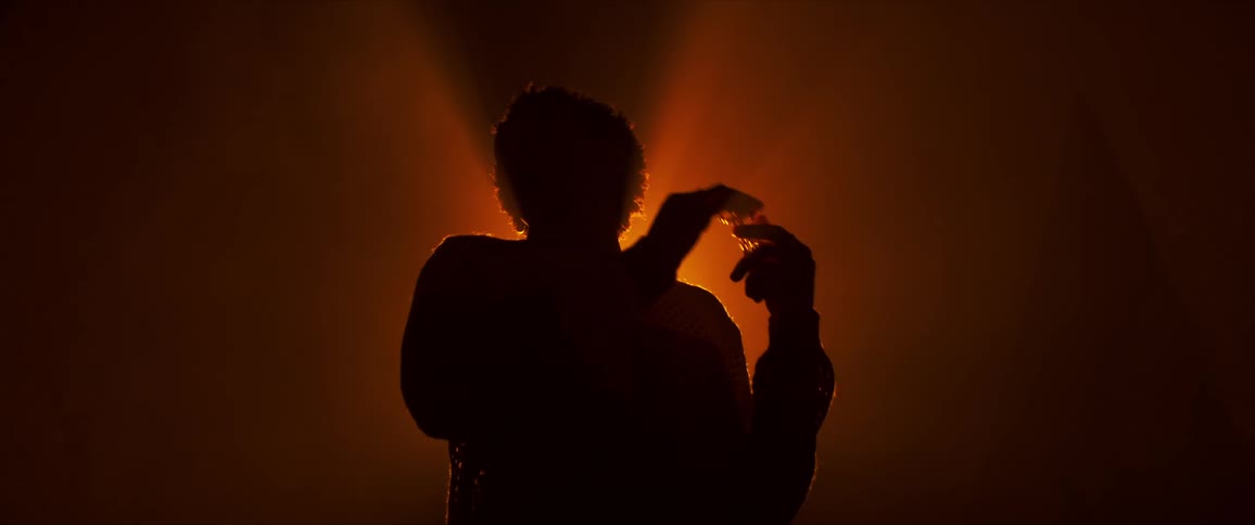 A person dances beneath a bright light resulting in only their silhouette being visible
