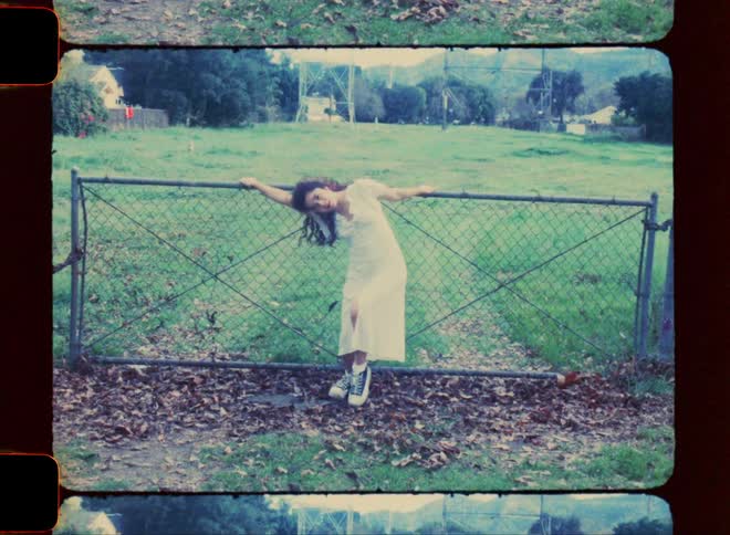 Woman in long white dress dancing amidst a fence in a natural field