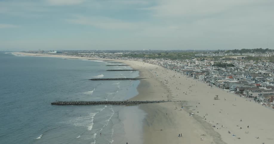 Piers stretch into the ocean from a beach located next to a metro area