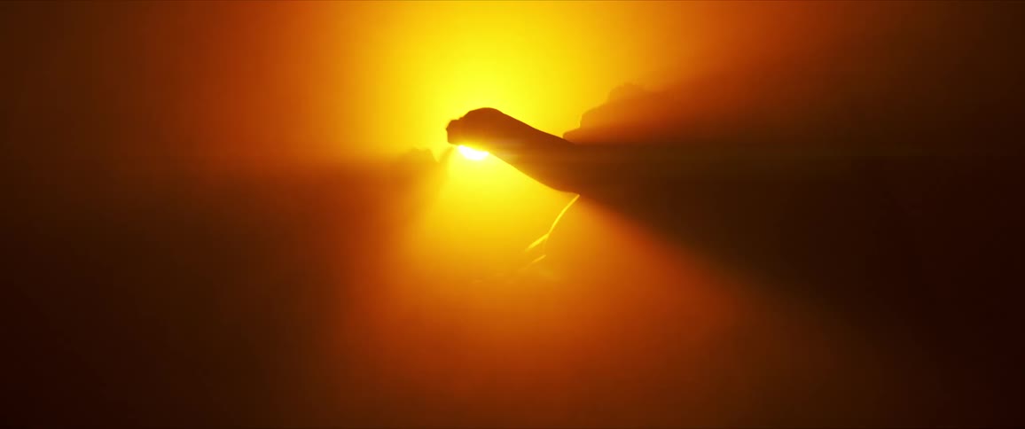 Silhouette of a person dancing against a bright yellow and orange halo of light