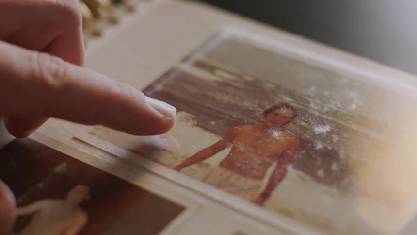 A person points their finger at a photograph in an album