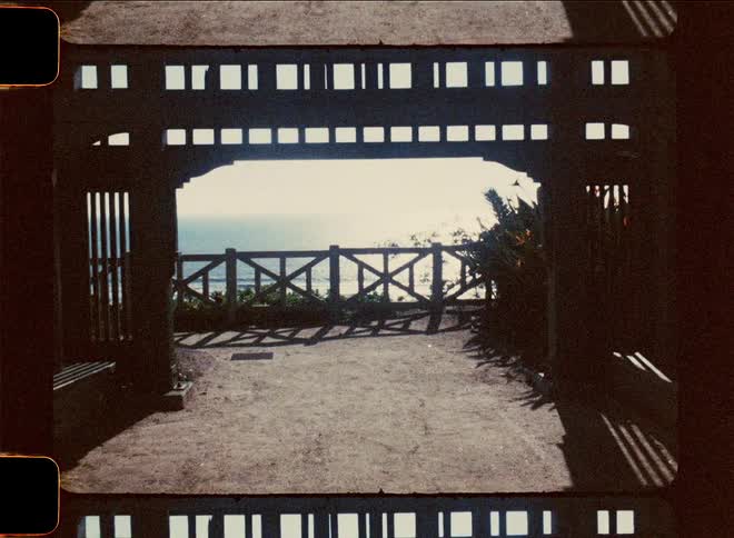 Silhouette of a darkened structure with patterned opening frames overlooking the ocean