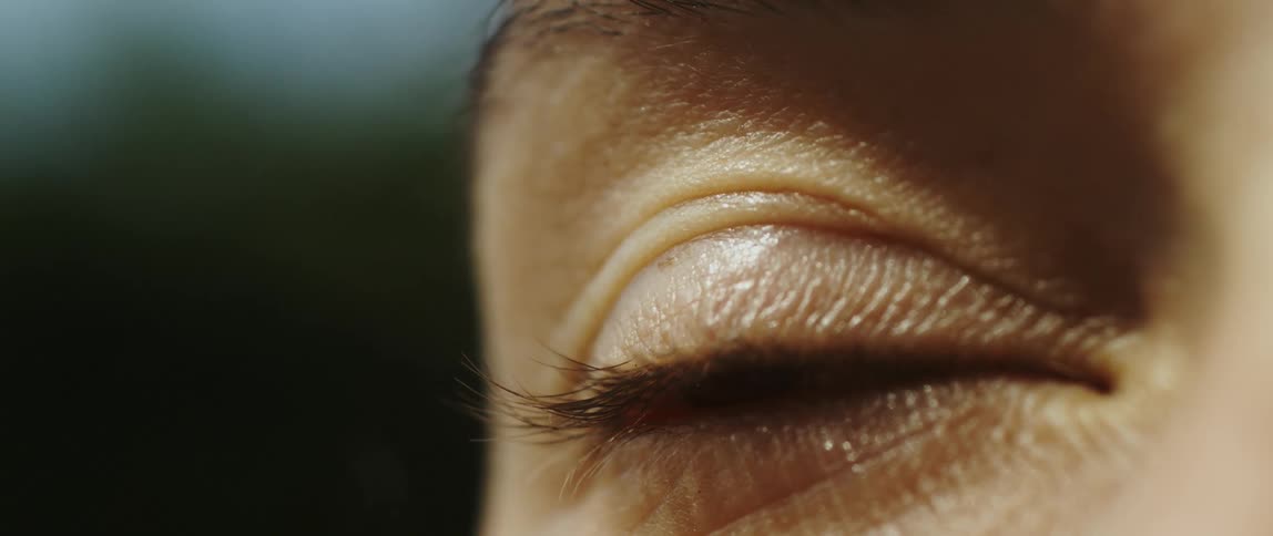 A person with brown eyes slowly blinks