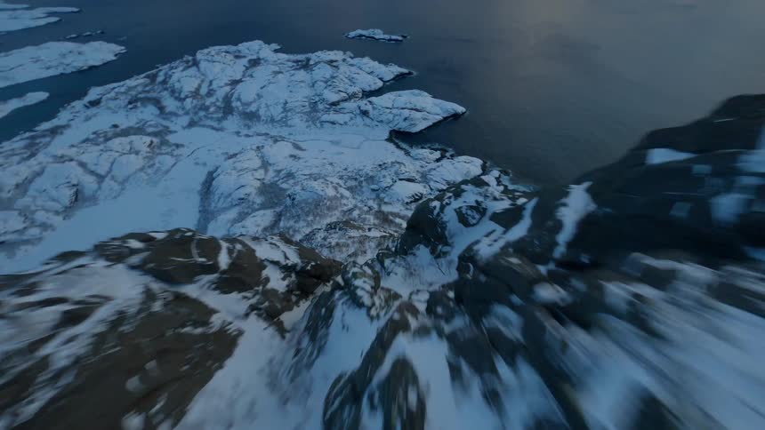 Aerial view of a snowcovered coastline with the sea visible on a cloudy morning