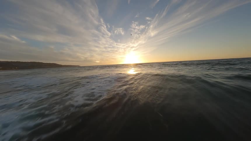 Aerial scene of a beach with a sun on the horizon