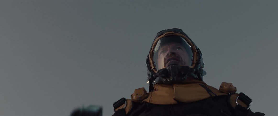 A man wearing an orange space suit using a futuristic tool