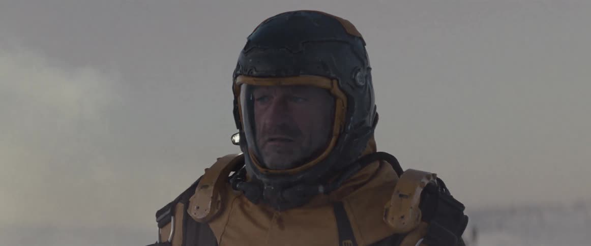 A man in a futuristic outfit and helmet in a fog passes in front of him