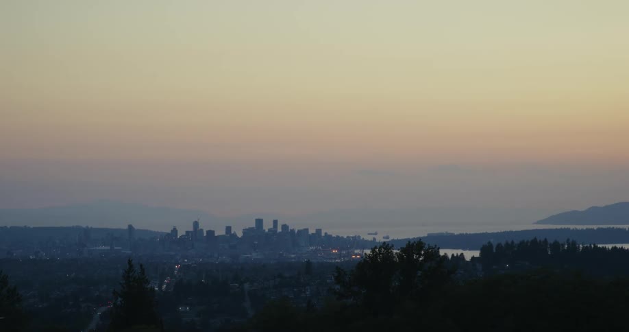 Panoramic view of a city at dusk with silhouettes of buildings