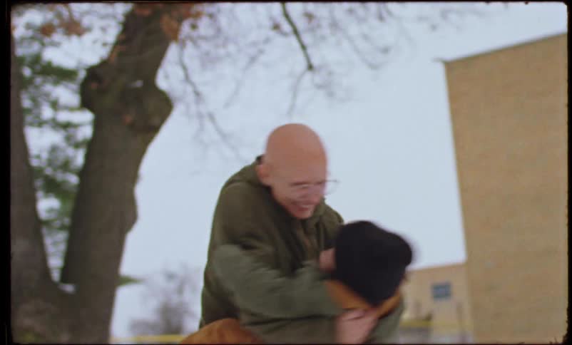 A mother spins her child around in the snow outside of a school