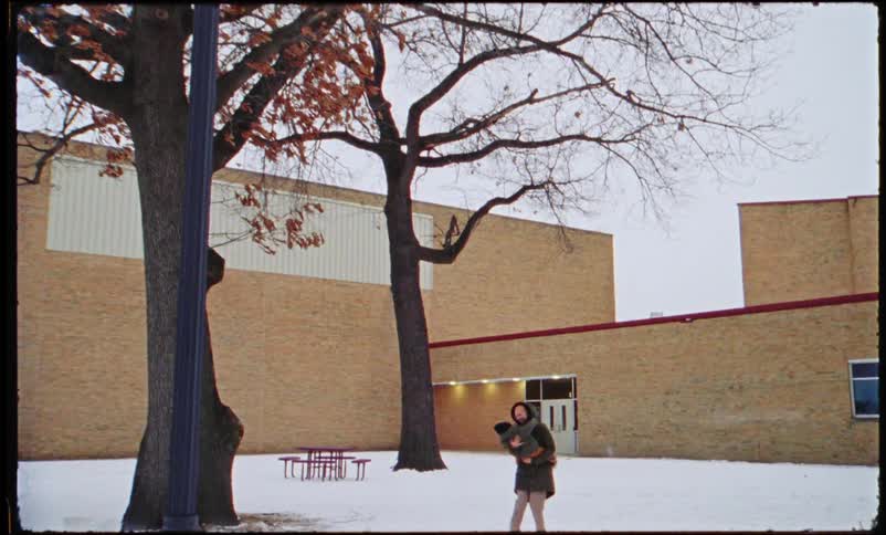 A mother spins her son around playfully outside of a elementary school