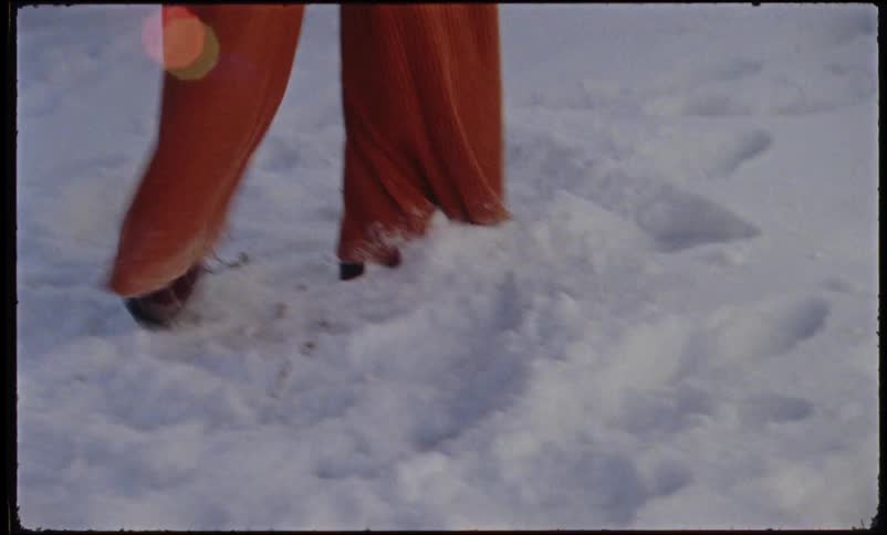 Mother holding her little daughter on her lap while playing with her in the snow