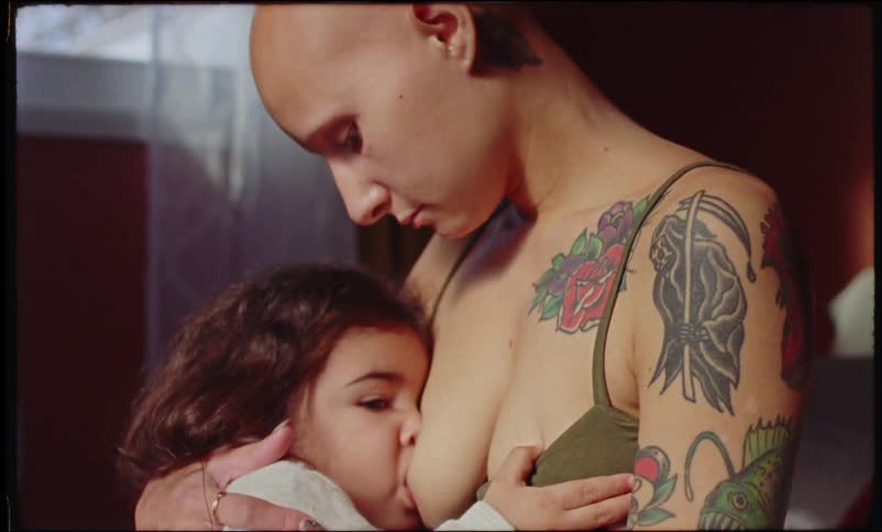 Mother caresses her toddler while breastfeeding her
