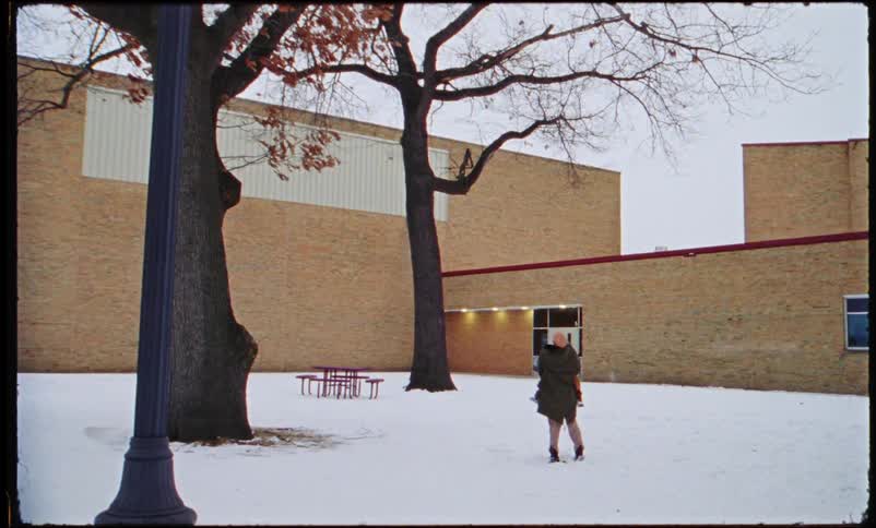 A mother dances by spinning her child around outside of a school